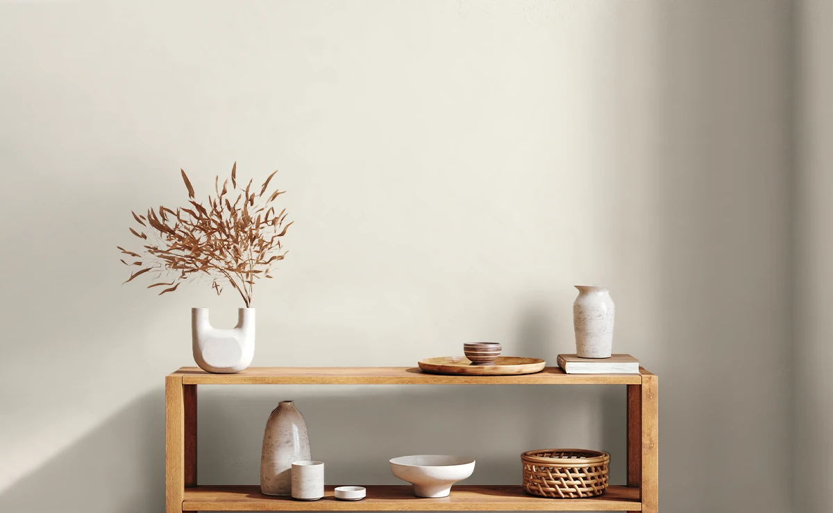 Modern interior featuring a wooden shelf displaying decorative items such as vases and bowls, accented by a minimalist floral arrangement. The wall uses Nippon Paint Acrylic 5170 Wall Sealer for long-lasting and flawless finish free from efflorescence.