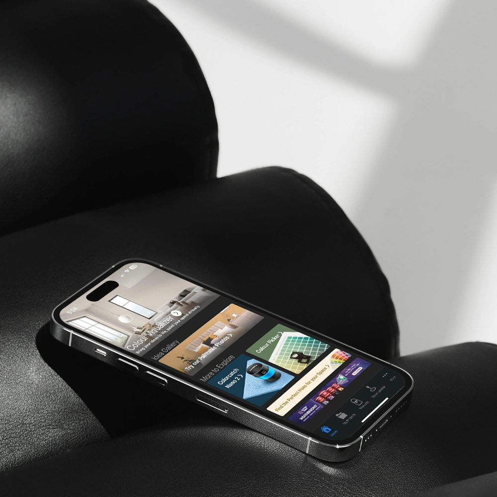 Smartphone displaying the Nippon Paint app on a black leather surface, showcasing color palette options and design ideas for home improvement.